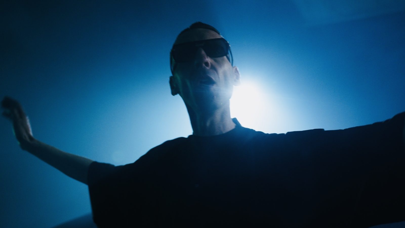 A backlit figure with arms spread in a music video
